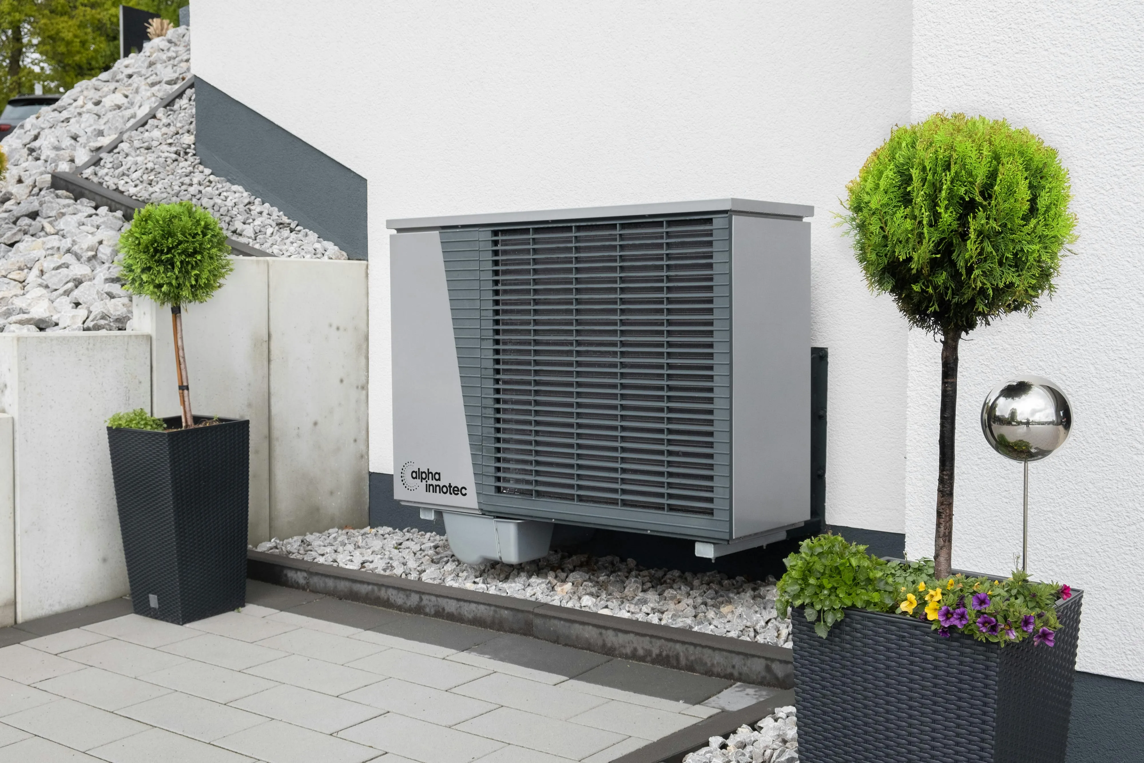 A heat pump outdoor unit fitted against a brick house wall