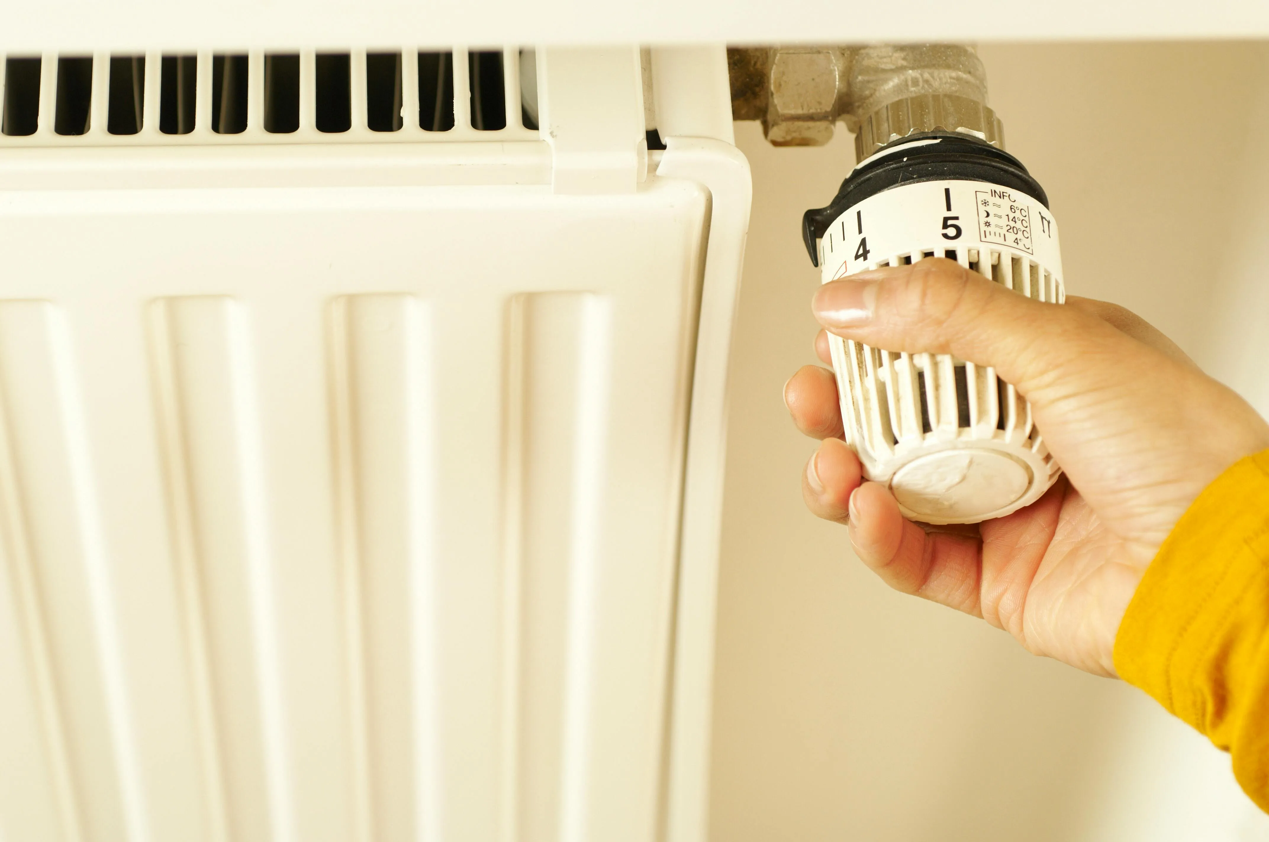 An engineer working near a sash window above a column radiator — radiator upgrades are a big part of installation week in older Leicester homes.