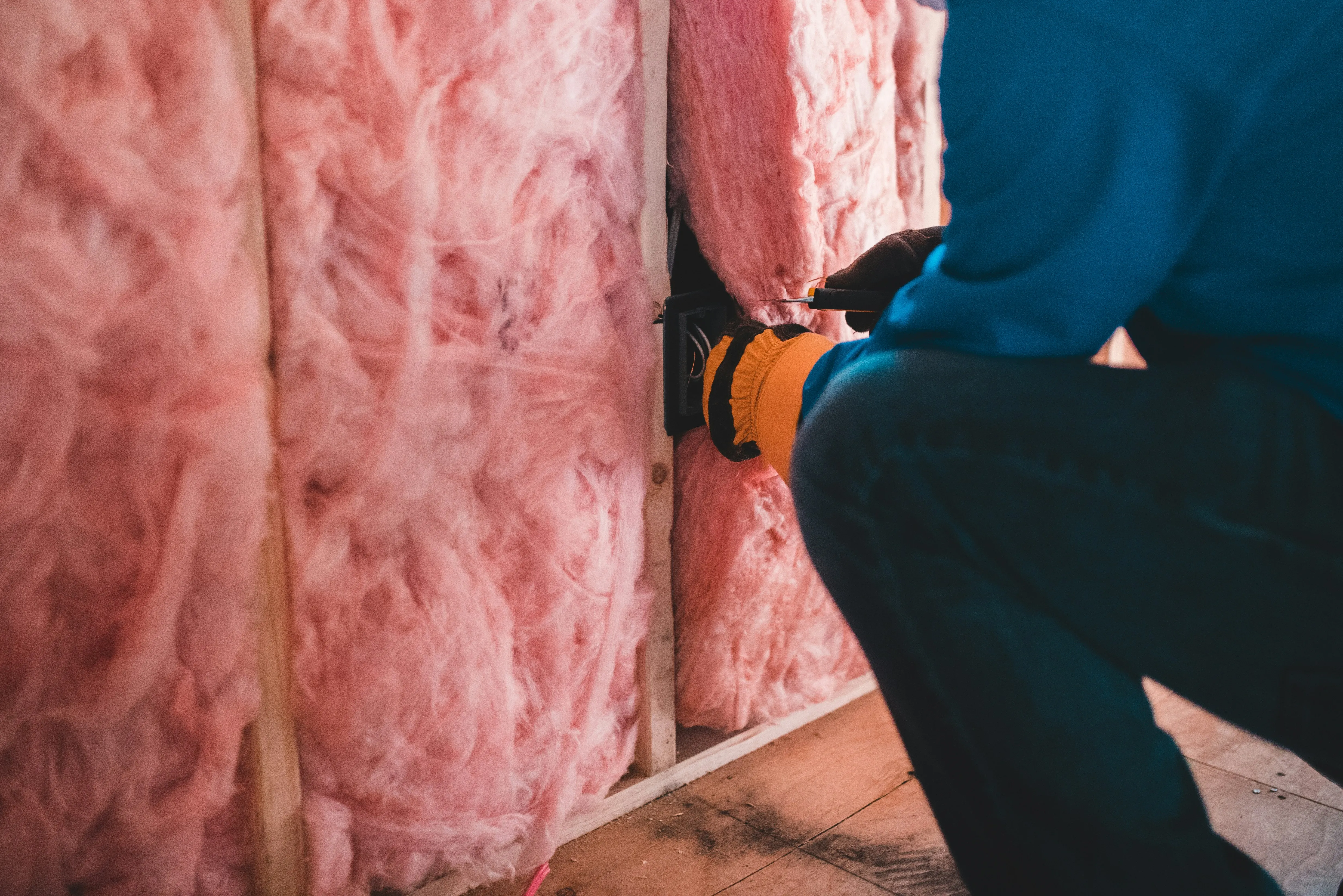 Insulation fitted between timber studs — cheap loft and floor insulation before a heat pump can mean a smaller unit and smaller bills.