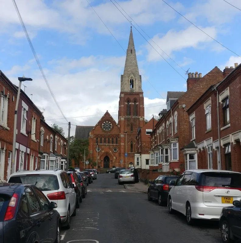 A narrow Leicester street of bay-window Victorian terraces with a church spire in the distance — older housing stock representative of the kind we install heat pumps in across the wider Leicester area, including parts of Aylestone.